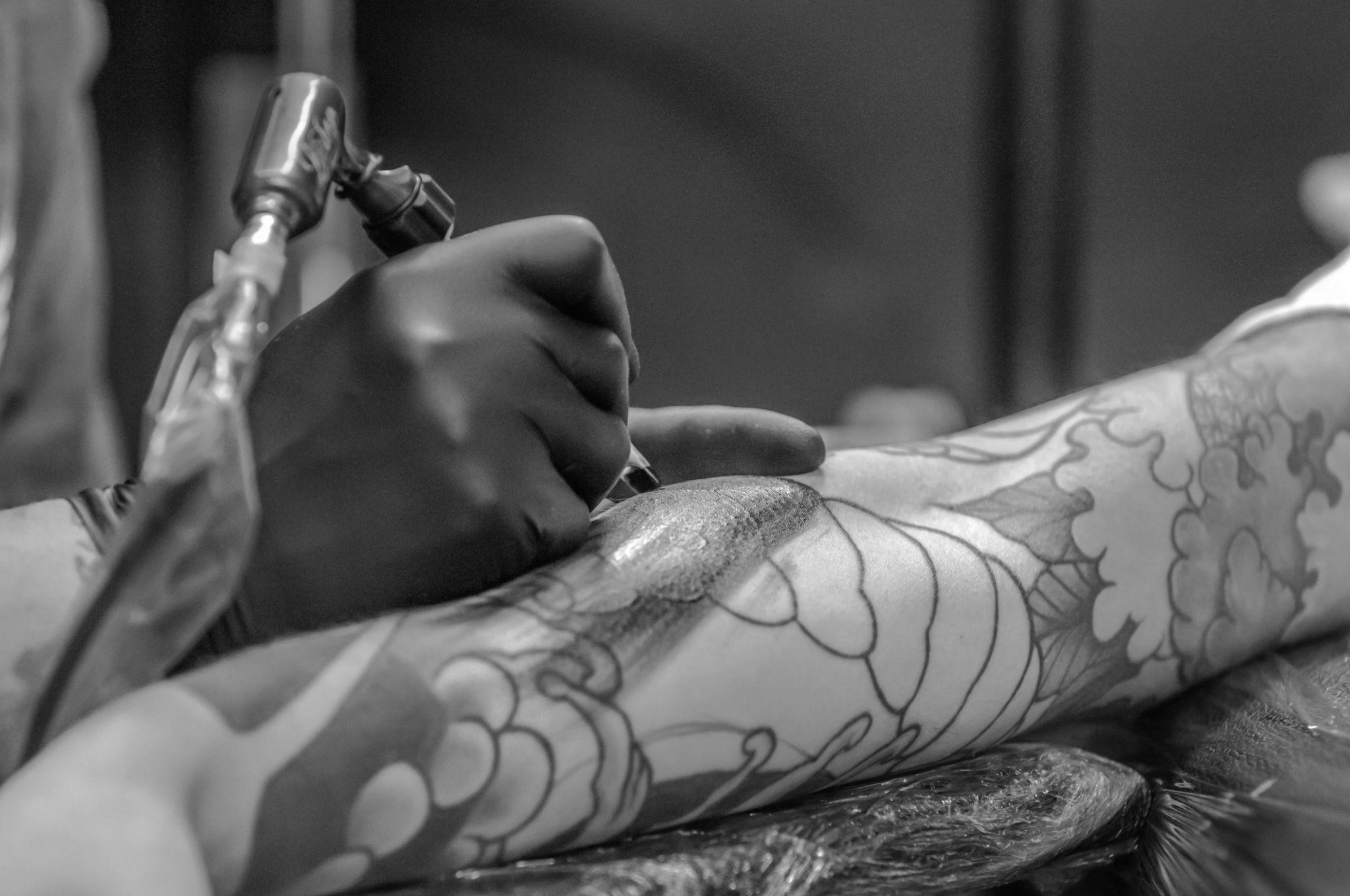 artist applying a full sleeve tattoo