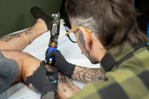 Artist doing a tattoo on a client forearm Artist doing a tattoo on a client’s forearm with a tattoo machine